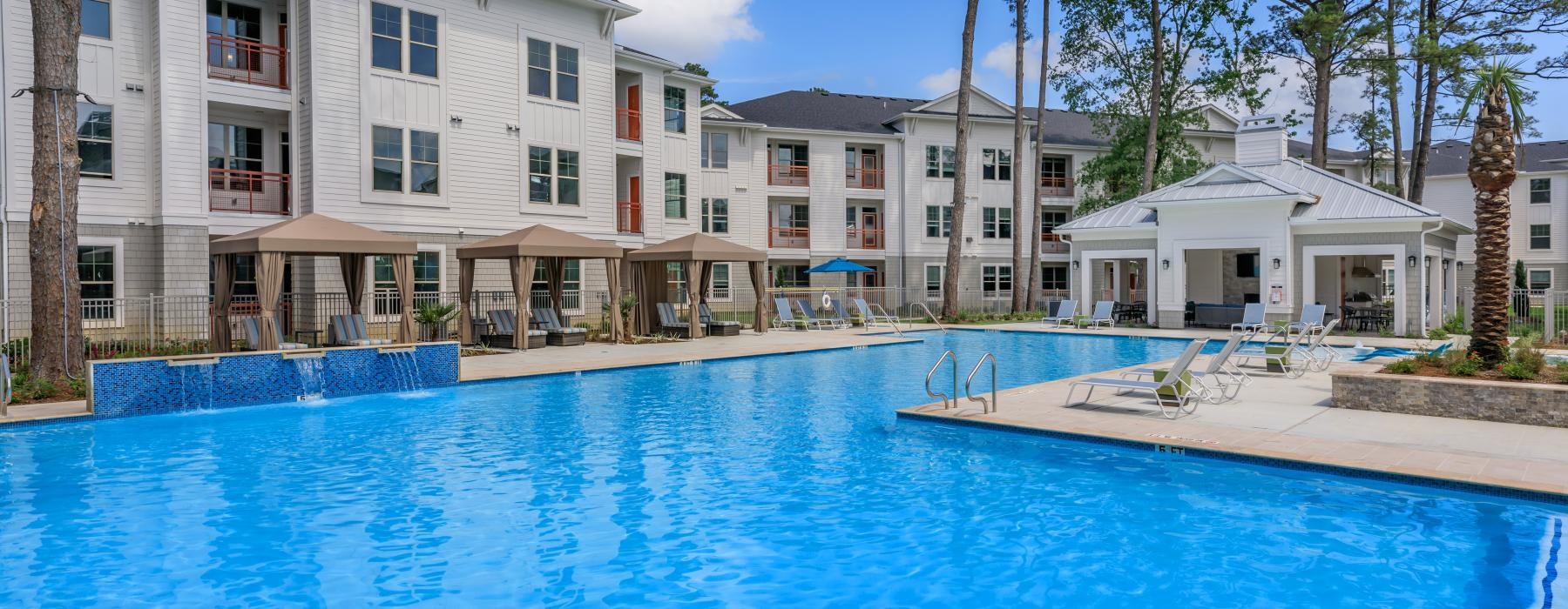 a swimming pool in front of a row of white buildings